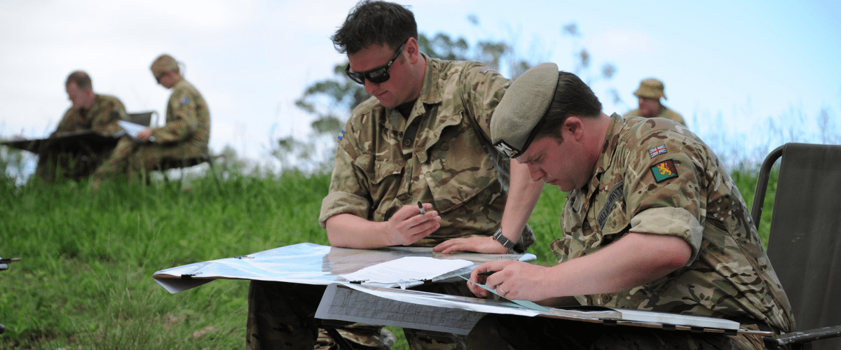 Defense mapping in use - soldiers viewing maps and charts in the field